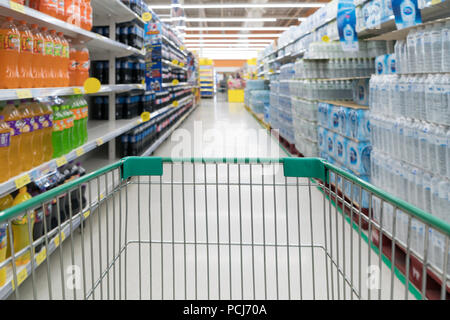 Abstract foto sfocata del negozio con carrello in department store bokeh sfondo. Supermercato corsia con vuoto verde carrello Foto Stock
