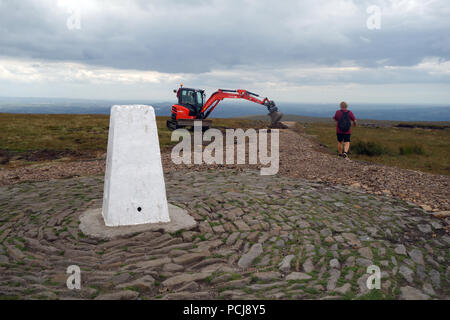 Uomo che cammina vicino al lavoro di scavo sul nuovo percorso essendo costruito che conduce fino alla colonna di Trig sul Vertice di Pendle Hill, Lancashire, Inghilterra, Regno Unito Foto Stock