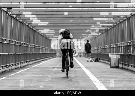 Uomo in sella alla sua moto nel ciclismo su pista Williamsburg Bridge, Brooklyn, New York City, Stati Uniti d'America. Immagine in bianco e nero. Foto Stock