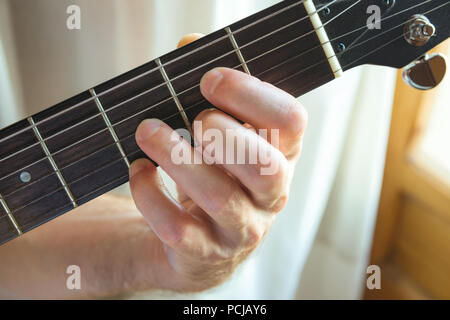 Giovane chitarrista holding fret board di suonare la chitarra corda dalla finestra. La musica che compongono la creatività dei talenti il concetto di prestazioni. Autentica vita candidi Foto Stock