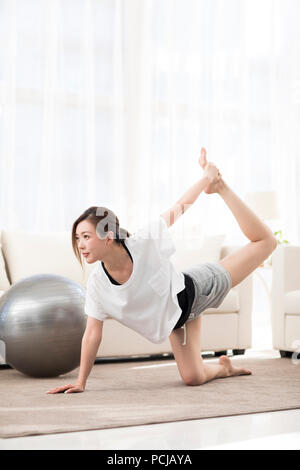 Giovane donna cinese a praticare yoga a casa Foto Stock