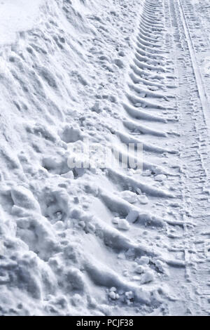 Le tracce nella neve, dettaglio orme trattore. Il trattore Orme nella neve in una giornata di sole. Foto Stock