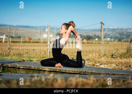 Donna sulla spiaggia Los Lances facendo un re pigeon Yoga posa, lo stretto parco naturale, Tarifa, Cadice, Andalusia, Spagna Foto Stock