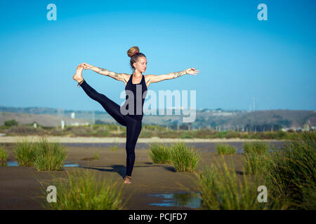 Donna sulla spiaggia Los Lances facendo mano alla punta del piede yoga posa, lo stretto parco naturale, Tarifa, Cadice, Andalusia, Spagna Foto Stock