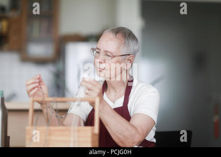 Donna seduta al tavolo che fissa una collana Foto Stock