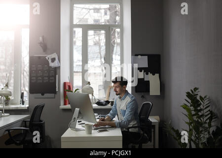 Giovani intelligenti barbuto uomo che lavora presso i moderni loft studio-offi Foto Stock