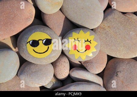 Pietra dipinta con faccina sorridente sulla spiaggia di ciottoli della Jurassic Coast in Devon Foto Stock