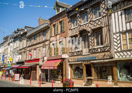 Scena di strada con antiche in legno e muratura negozi di high street in Cormeilles, Normandia, Francia in una giornata di sole con cielo blu chiaro Foto Stock