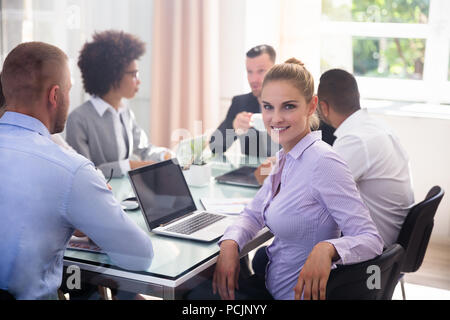 Ritratto di un felice giovane imprenditrice seduta in ufficio Foto Stock