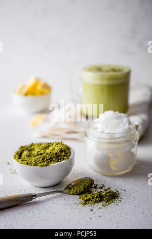 BULLETPROOF MATCHA. Ketogenic dieta cheto bevanda calda. Il tè matcha miscelato con olio di noce di cocco e il burro. Tazza di bulletproof matcha e ingredienti su sfondo bianco Foto Stock