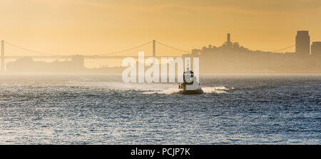 Barca nella Baia di San Francisco al tramonto con nebbia Foto Stock