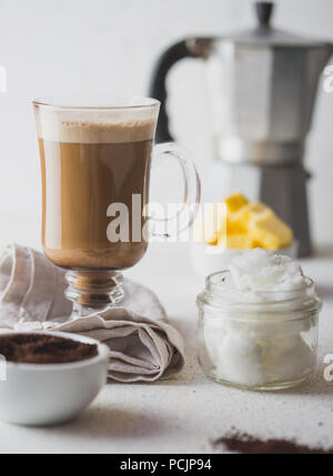 BULLETPROOF caffè. Ketogenic dieta cheto coffe miscelato con olio di noce di cocco e il burro. Tazza di caffè antiproiettile e gli ingredienti su sfondo bianco Foto Stock