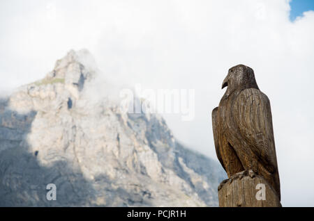 Aquila di legno scultura in Svizzera con una montagna (Dündenhorn) in background Foto Stock