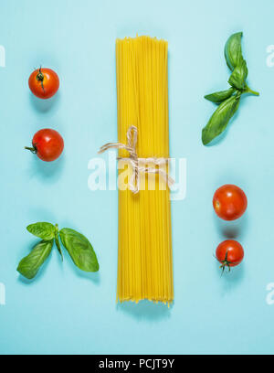 Bundle di italiano gli spaghetti legati con spago giacente su sfondo blu. Vista superiore Foto Stock