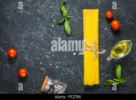 Bundle di italiano gli spaghetti legati con spago giacente sulla pietra scura sullo sfondo. Vista superiore e spazio di copia Foto Stock