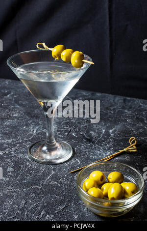 Martini cocktail con olive verdi sul tavolo di pietra dello sfondo. Foto Stock