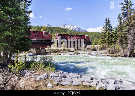 Un treno merci della Canadian Pacific Railway attraversando il Fiume Bow nelle montagne rocciose presso la città di Lake Louise, Alberta, Canada Foto Stock