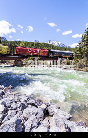 Un treno merci della Canadian Pacific Railway attraversando il Fiume Bow nelle montagne rocciose presso la città di Lake Louise, Alberta, Canada Foto Stock