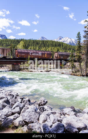 Un treno merci della Canadian Pacific Railway attraversando il Fiume Bow nelle montagne rocciose presso la città di Lake Louise, Alberta, Canada Foto Stock