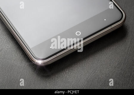 Uno smartphone si appoggia su un nero office desk close-up. Foto Stock