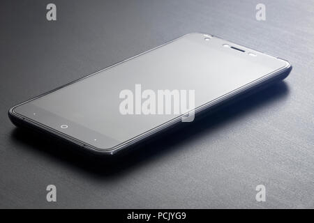 Uno smartphone si appoggia su un nero office desk close-up. Foto Stock