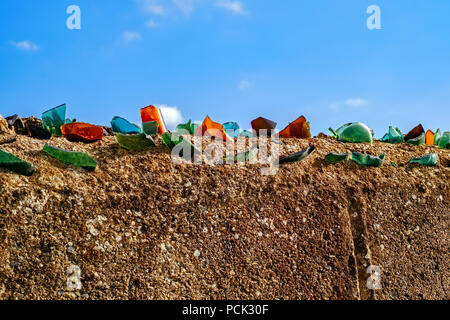 Cocci di bottiglia di vetro sul muro di mattoni Foto Stock