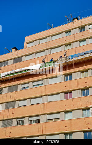 Malaga, Spagna - 23 febbraio 2018. I lavoratori sulla impalcatura esterna ascensore per riparare l'edificio Foto Stock