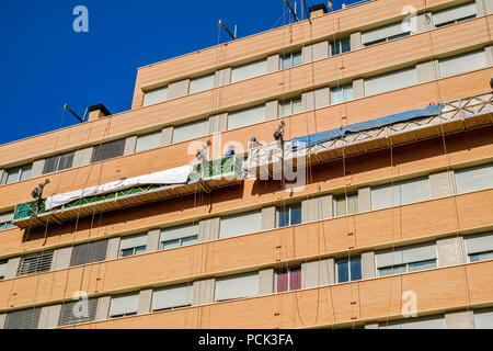 Malaga, Spagna - 23 febbraio 2018. I lavoratori sulla impalcatura esterna ascensore per riparare l'edificio Foto Stock