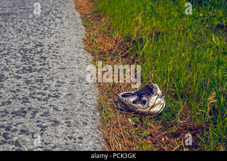 Rotto abbandonato lo sport scarpe sul lato della strada Foto Stock