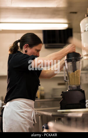 Chef usando una smerigliatrice in una cucina commerciale Foto Stock