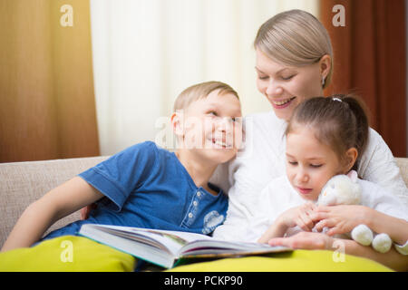 Bella madre è la lettura di un libro ai suoi figli. Sorella e fratello è in ascolto di una storia. Foto Stock