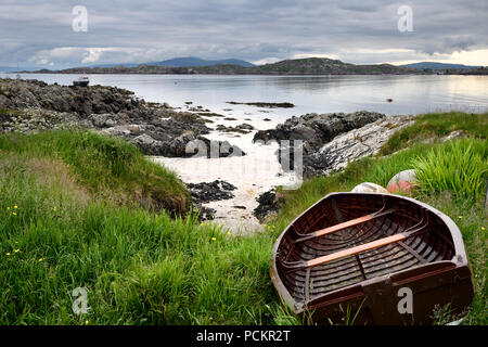 Spiaggia rocciosa di Isola di Iona con spiaggiata barca con Fionnphort Isle of Mull e montagne di Ben più passato Suono di Iona Ebridi Interne in Scozia UK Foto Stock