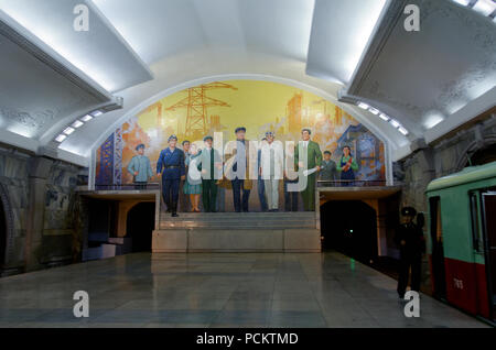 Treno della metropolitana nella piattaforma della stazione di ripresa da un murale per celebrare il leader supremo e dei lavoratori sulla metropolitana di Pyongyang, Corea del Nord Foto Stock