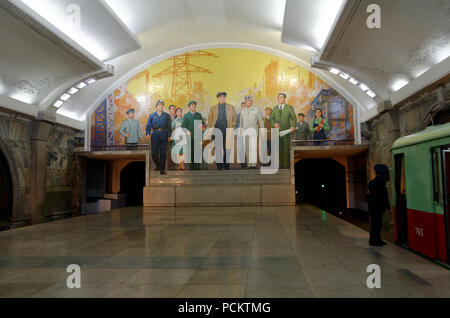 Treno della metropolitana nella piattaforma della stazione di ripresa da un murale per celebrare il leader supremo e dei lavoratori sulla metropolitana di Pyongyang, Corea del Nord Foto Stock