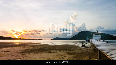 Tramonto con drammatica cielo sopra seascape, la spiaggia e il molo view Foto Stock