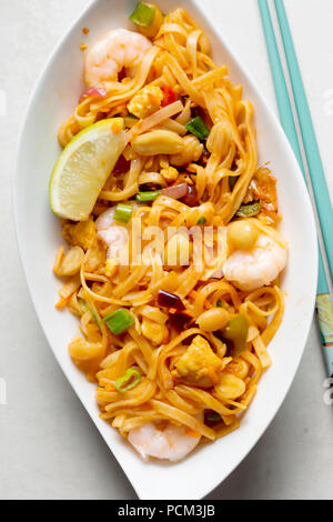 Pad Thai noodles con Pollo, gamberi e verdure miste, arachidi tritate, scalogno e uno spicchio di lime Foto Stock