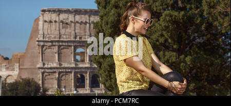 Felice giovane turista donna in giallo camicetta in Italia a Roma seduta sul parapetto Foto Stock