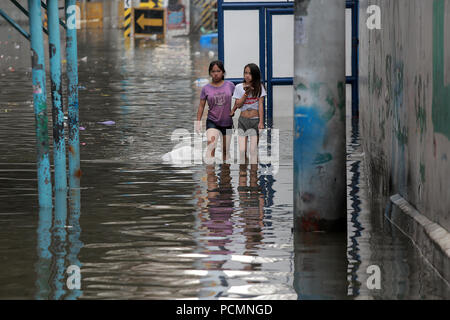 Quezon City, Filippine. Il 3° agosto 2018. Residenti wade attraverso una strada allagata dopo forti piogge monsoniche nella città di Quezon, Metro Manila, Filippine, 3 Agosto, 2018. Diverse strade e zone residenziali in Metro Manila furono sommerse in acque alluvionali a causa delle continue piogge monsoniche. Credito: Rouelle Umali/Xinhua/Alamy Live News Foto Stock