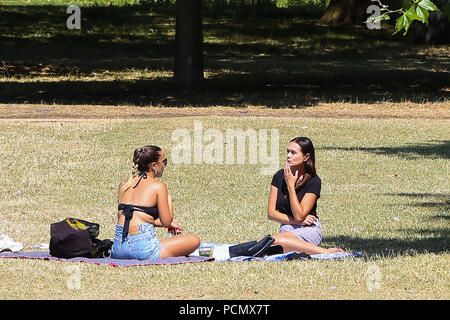 Hyde Park. Londra. Regno Unito 3 Aug 2018 - Due donna seduta su bruciò erba secca in Hyde Park su un altro molto calda giornata nella capitale. Secondo il Met Office l ondata di caldo è alla continua nel Regno Unito e in alcune parti d'Europa nei prossimi giorni con temperature record previsto. Credito: Dinendra Haria/Alamy Live News Foto Stock