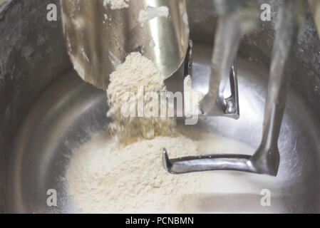 Caricamento di farina in un impasto industriale miscelatore. Vista ravvicinata. Foto Stock