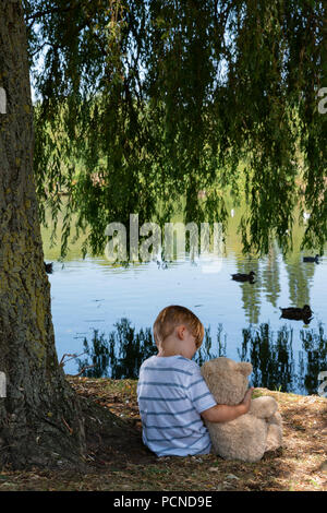 Bambino in posizione di parcheggio con il giocattolo di peluche Foto Stock