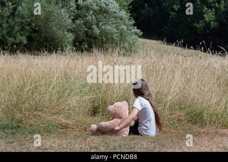 Bambina nel parco con il giocattolo di peluche Foto Stock