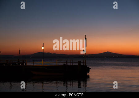 Un molo presso il lago Trasimeno (Umbria, Italia) al tramonto, con acqua bella riflessi e colori caldi Foto Stock