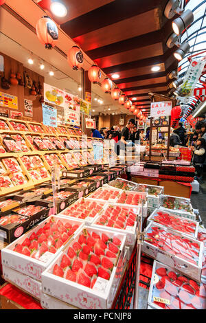 Kuromon Ichiba, mercato alimentare di Osaka. Negozio di stallo e la vendita di frutta con un display anteriore principalmente le fragole. Vista lungo contatore anteriore. Foto Stock