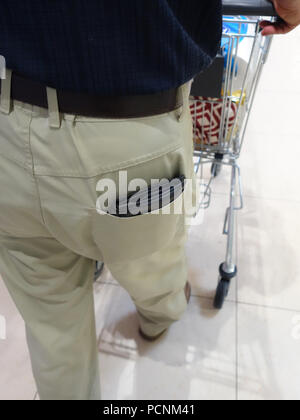 Uomo vecchio shopping nel supermercato con il suo portafoglio sul display completo fuori della sua tasca posteriore pronto per un pickpocket Foto Stock