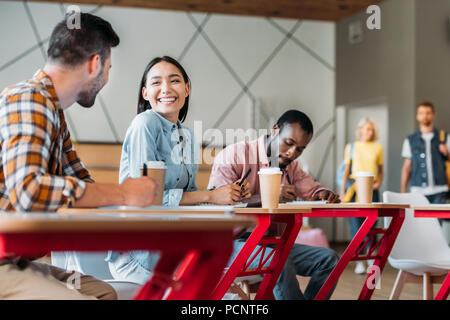 Felice giovani studenti a chattare in aula del collegio Foto Stock