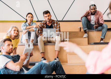 Elegante giovani studenti di trascorrere del tempo insieme al college sulle tribune di legno Foto Stock