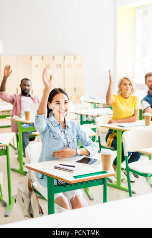 Giovani studenti alzando le mani per rispondere sulla questione degli insegnanti Foto Stock
