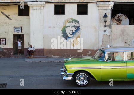 Caraibi Cuba, La Habana, scena di strada con graffiti di Che e auto d'epoca Foto Stock