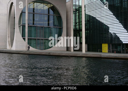 Un pedone a piedi lungo il fiume Spree incollando la moderna architettura della Marie-Elisabeth-Lüders house di Berlino. Foto Stock